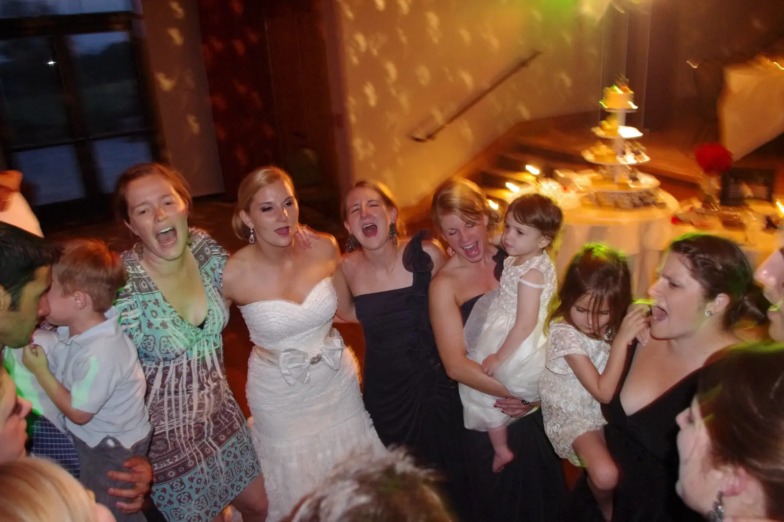 A bride singing and celebrating with family and young wedding guests on the dance floor