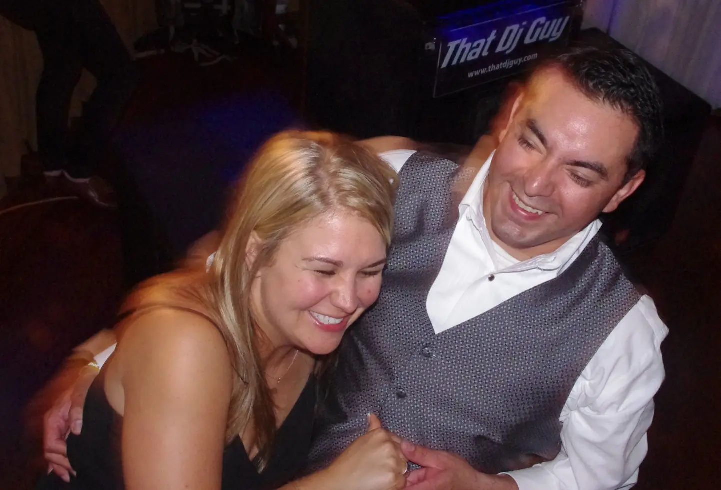 A newlywed couple laughing together on the dance floor