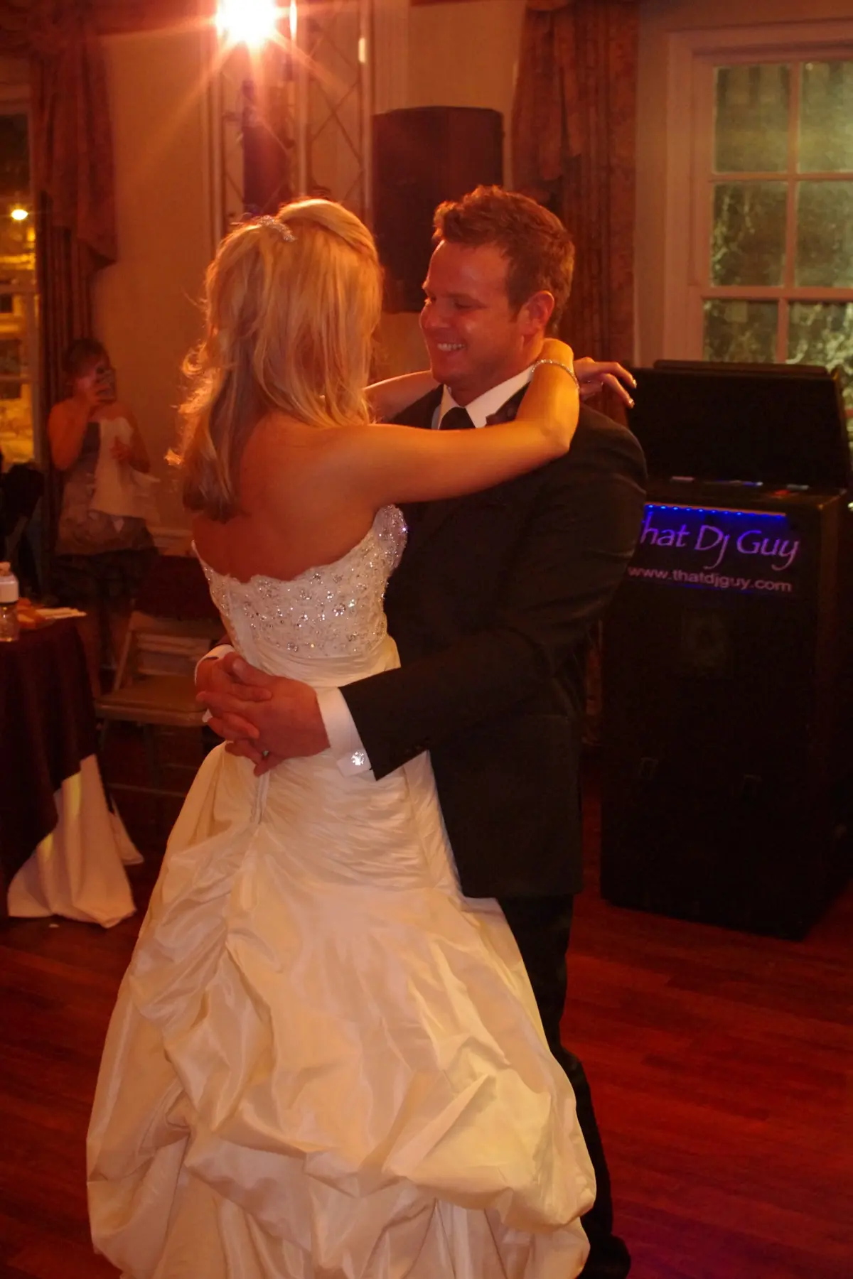 A newlywed couple dancing beside the illuminated ThatDjGuy sound system