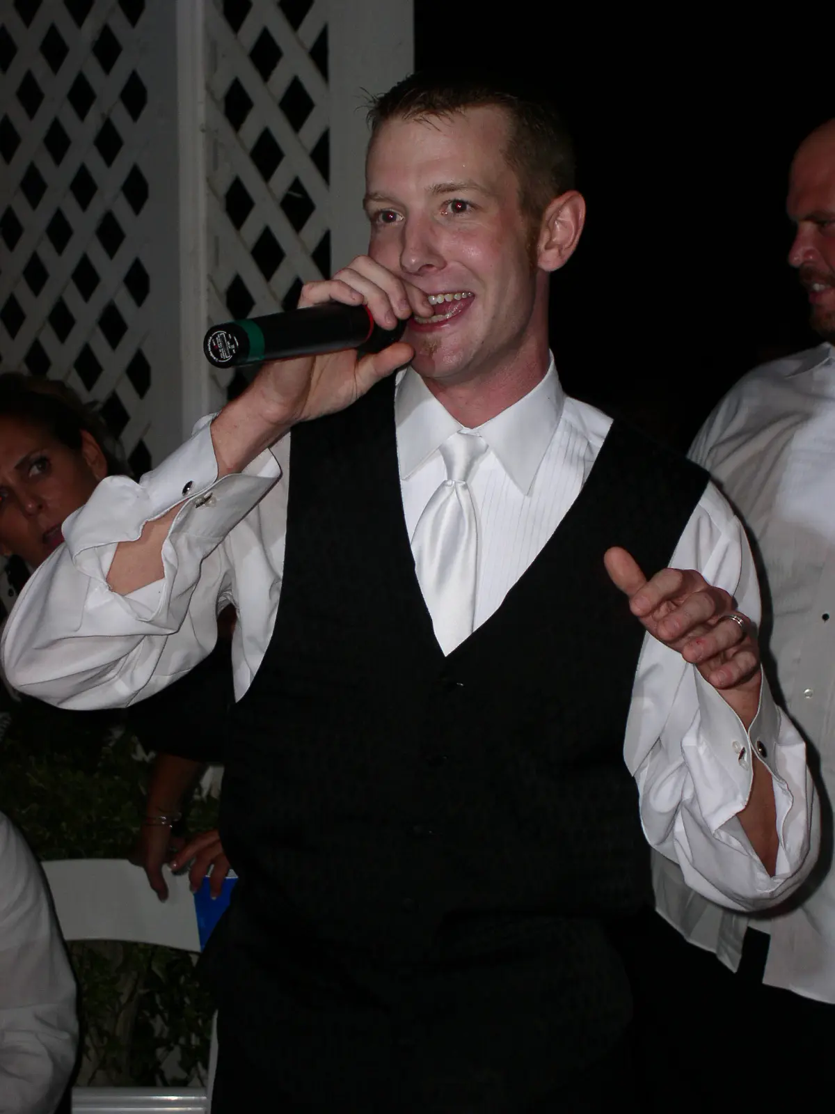 A groom singing karaoke at his wedding reception