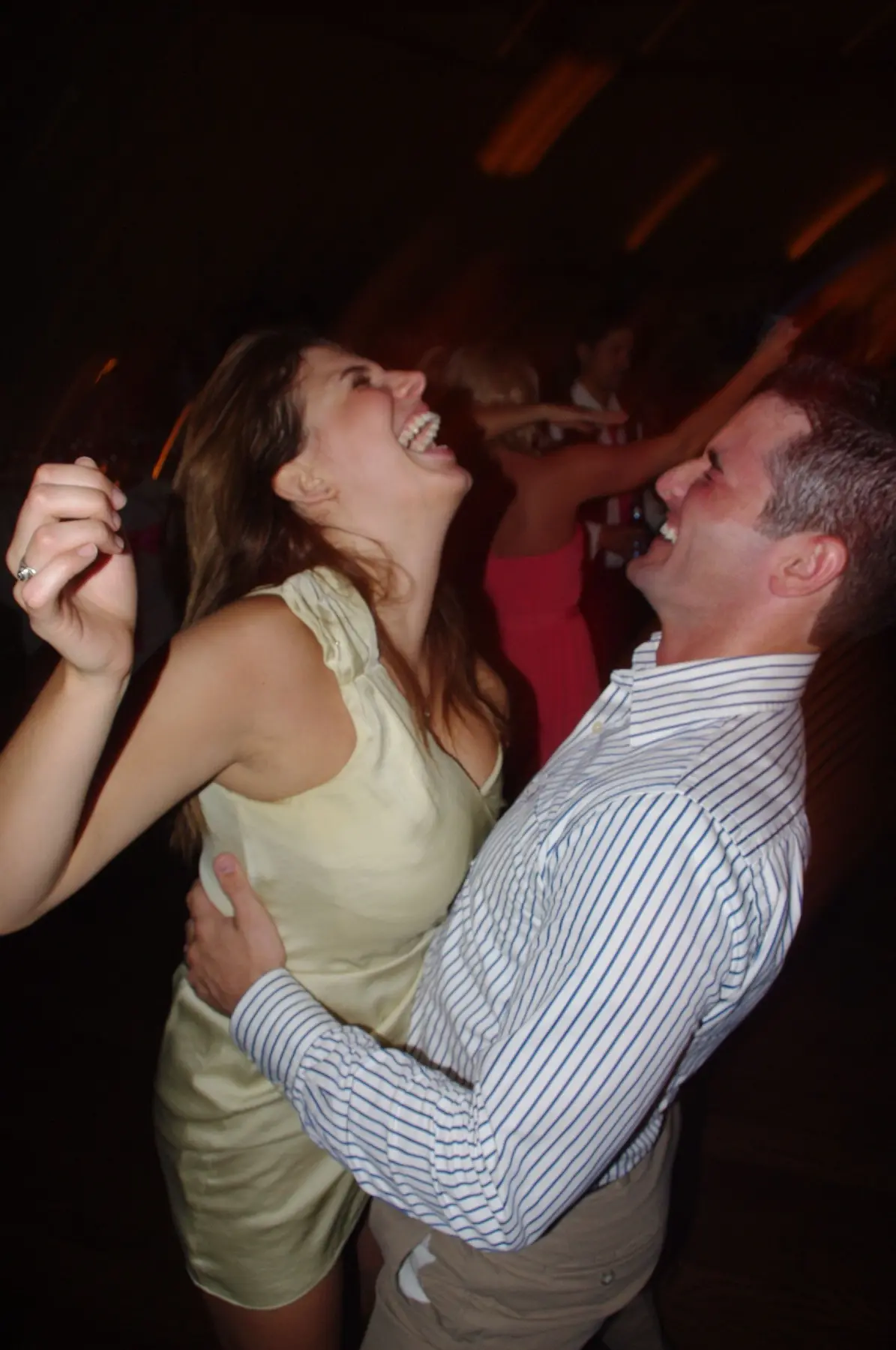 A couple laughing and dancing together at a lively party