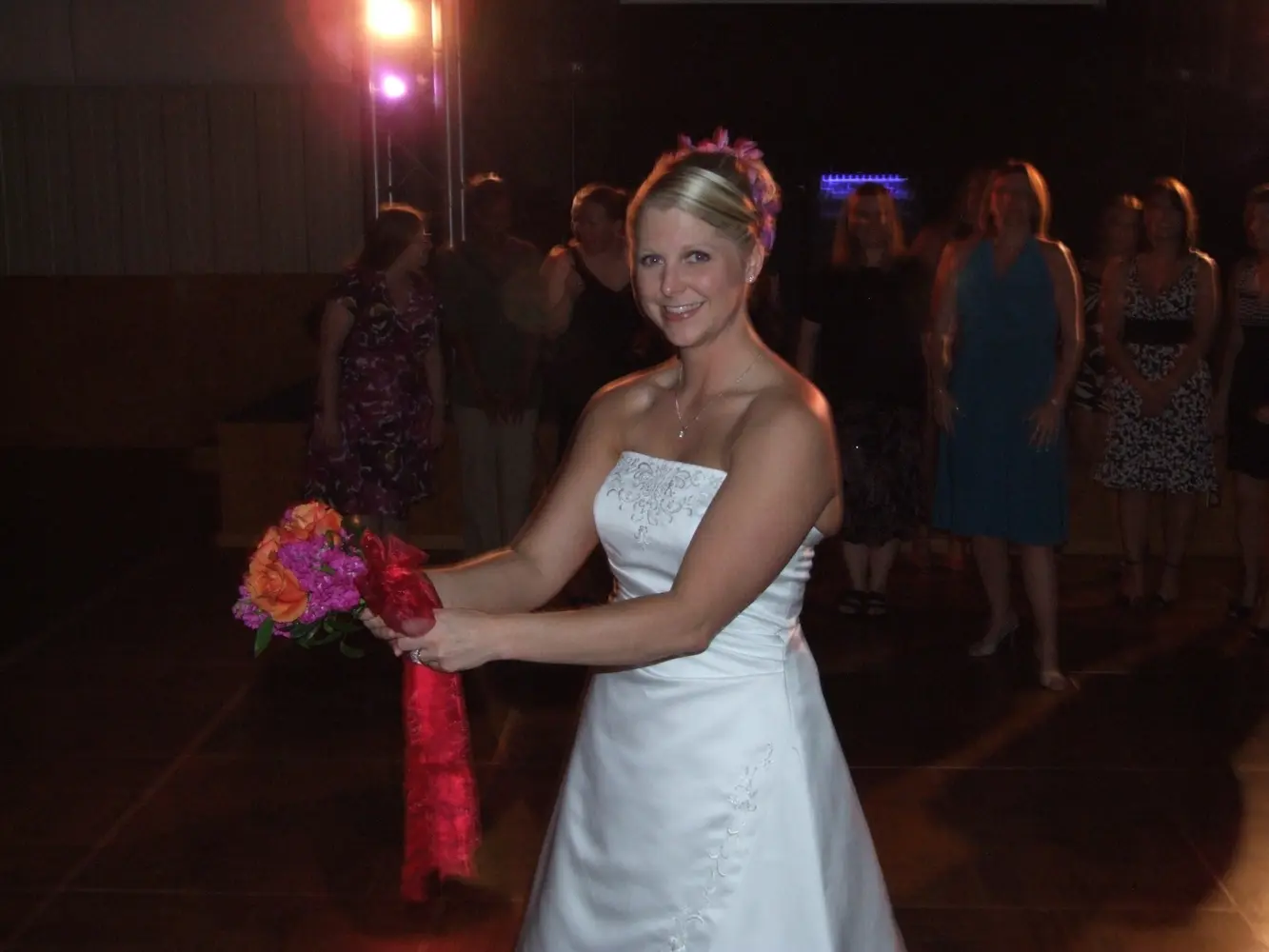 A bride smiling with her bouquet on the dance floor
