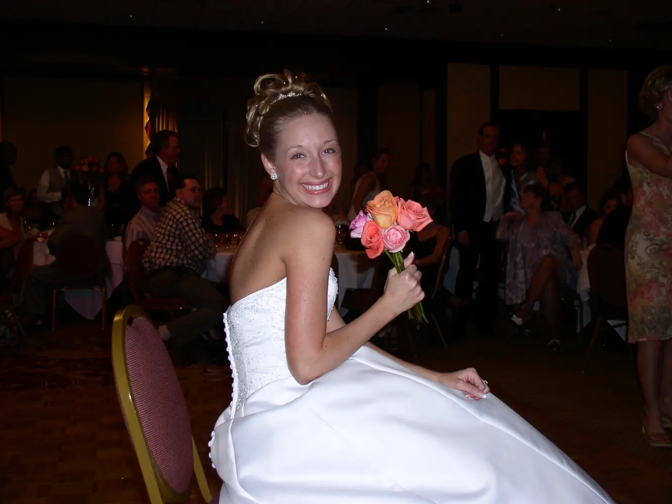 A bride smiling with her bouquet at the reception